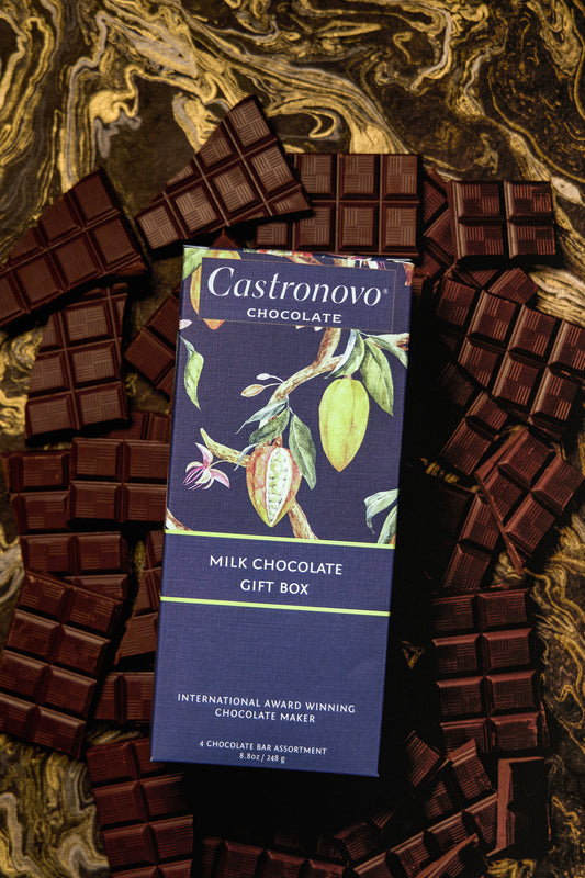 A Milk Chocolate Gift Box by Castronovo Chocolate, containing four bars of various chocolates, displayed on a marble surface.