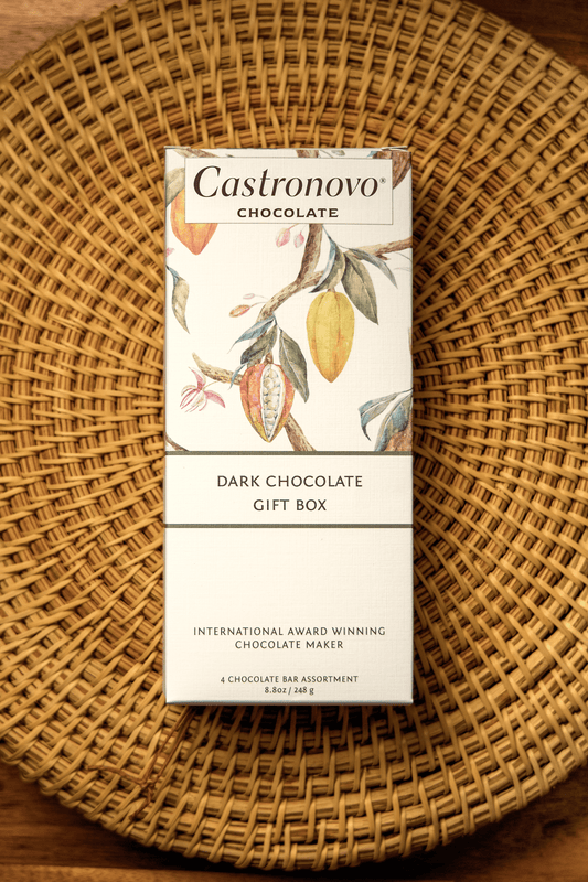 A packaged gift box of Castronovo dark chocolate bars with a floral design on the packaging, placed on a woven basket.