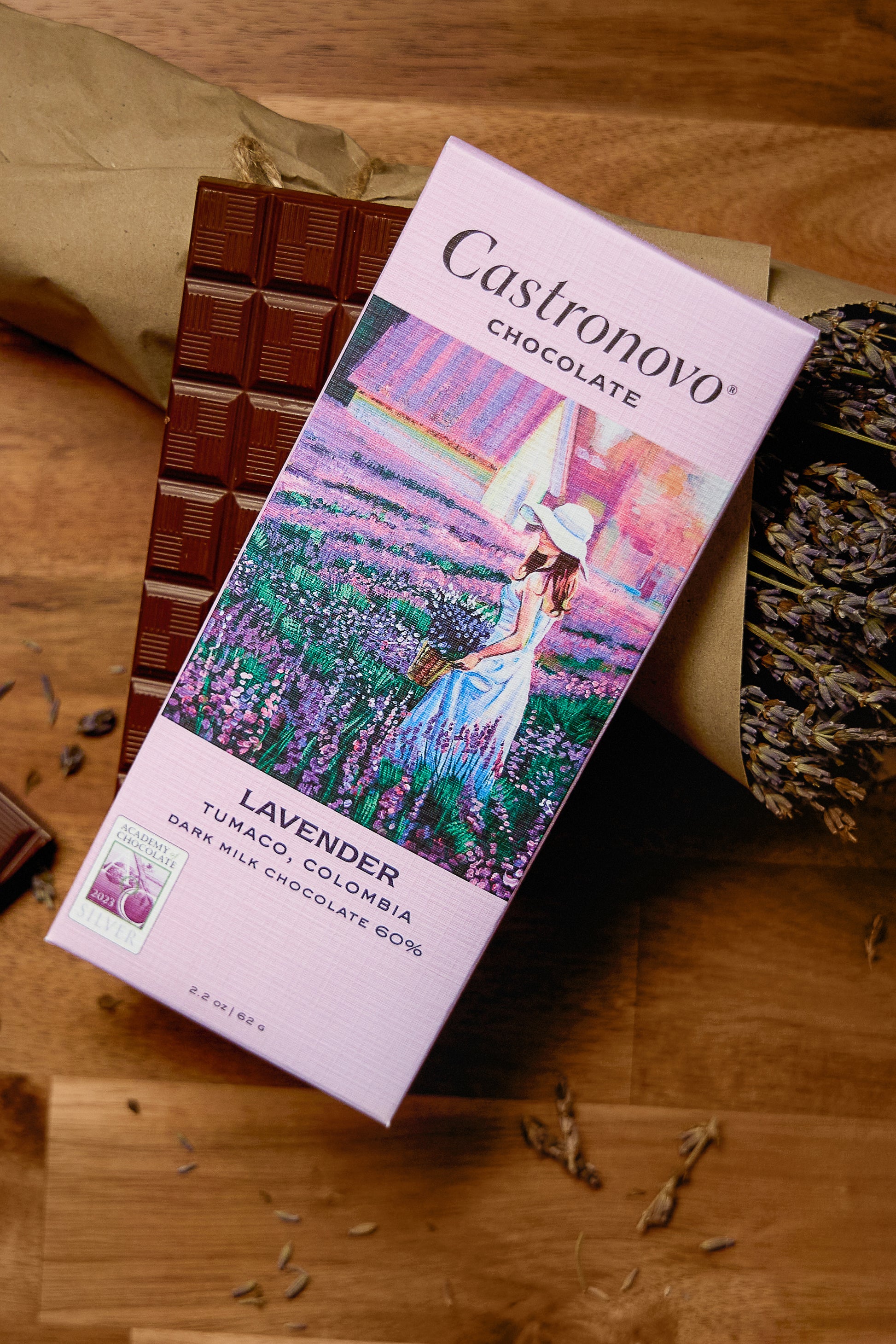A chocolate bar packaging with an image of a woman in a field of lavender, alongside pieces of dark milk chocolate.