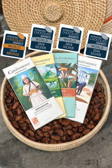 A selection of four award-winning chocolate bars presented in a basket, each with a label displaying the winning place and brand name.