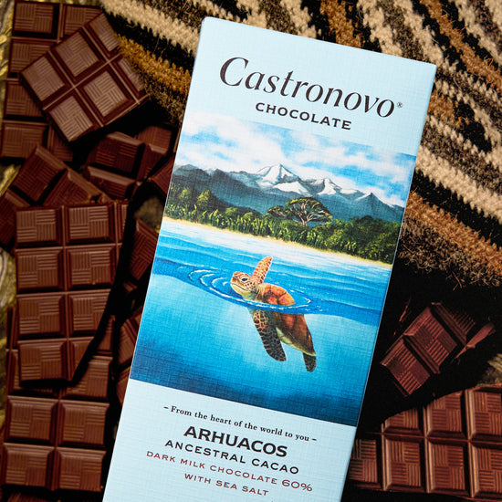 A bar of Castronovo chocolate with a turtle on the packaging, surrounded by multiple pieces of chocolate on a patterned surface.