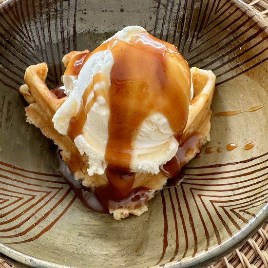 Image of "Lick My Spoon" brand caramel sauce on a scoop of vanilla ice cream inside a bowl 