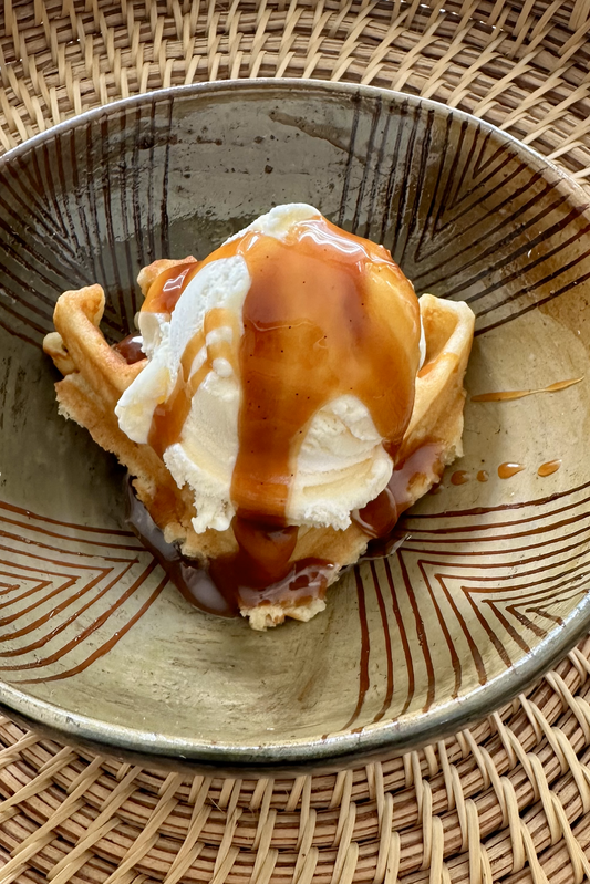 Image of "Lick My Spoon" brand caramel sauce on a scoop of vanilla ice cream inside a bowl 