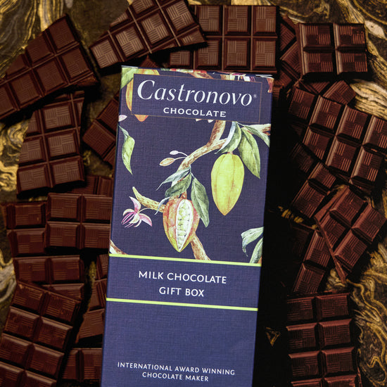 A Milk Chocolate Gift Box by Castronovo Chocolate, containing four bars of various chocolates, displayed on a marble surface.