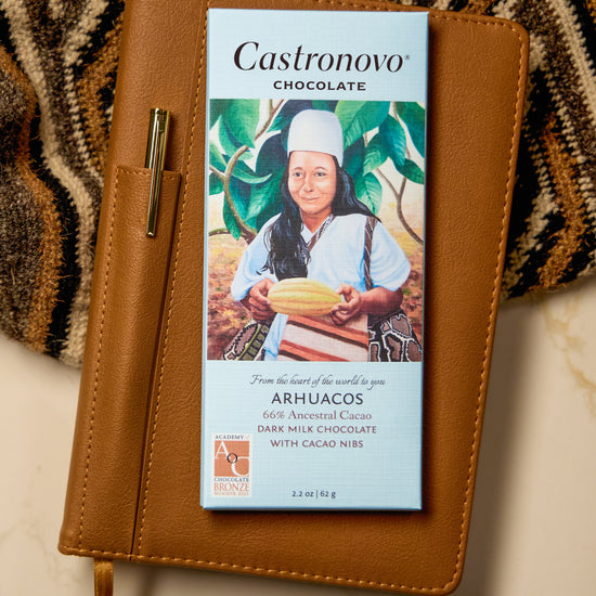Castronovo Chocolate bar with illustration of indigenous man holding cacao pod on cover against tan background 
