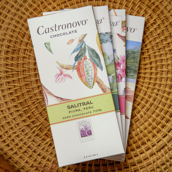 Collection of Castronovo chocolate bars on tan woven background with Salitral 70 percent dark chocolate on the top of the stack
