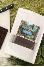 A chocolate chef tablet with a label showing the brand and possibly the Peruvian Amazonian landscape. The tablet is placed on a white paper, which is on a textured background.