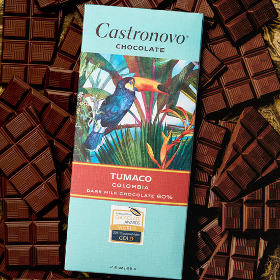 A chocolate bar packaging with the brand Castronovo Chocolate, the product name Tumaco, and an image of a colorful bird on the packaging, surrounded by pieces of dark chocolate.